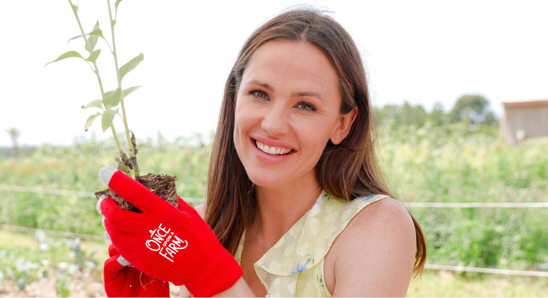 Jennifer Garner holding garden plant with red Once Upon a Farm brand gloves